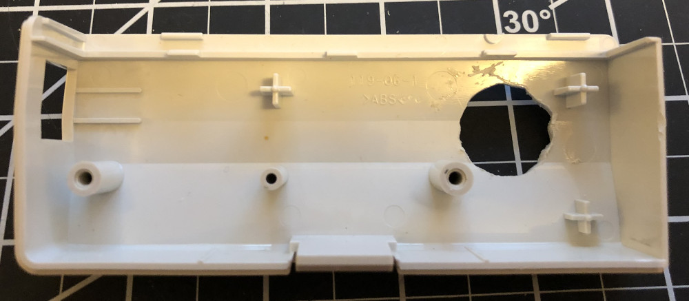 The inside of the plastic case of a Dreamcast modem with a large hole made in one side