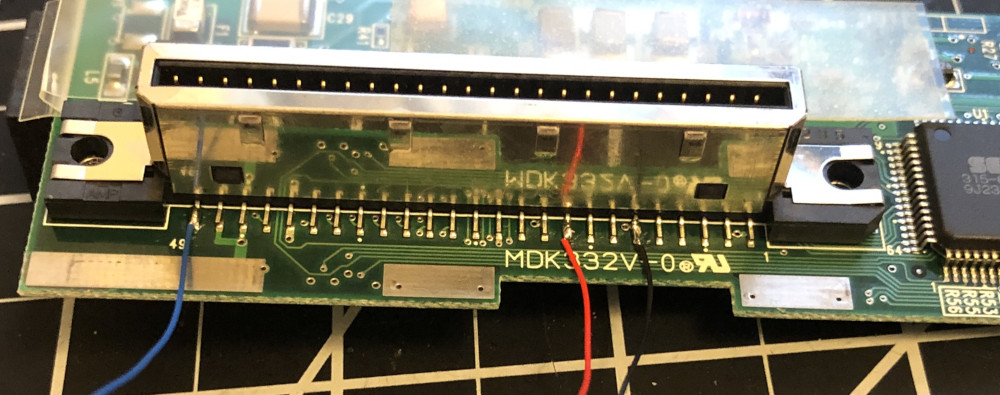 The G2 connector of a Dreamcast modem PCB with a black wire soldered to pin 11 (ground), a red wire soldered to pin 17 (+5V), and a blue wire soldered to pin 49 (MIDI OUT)